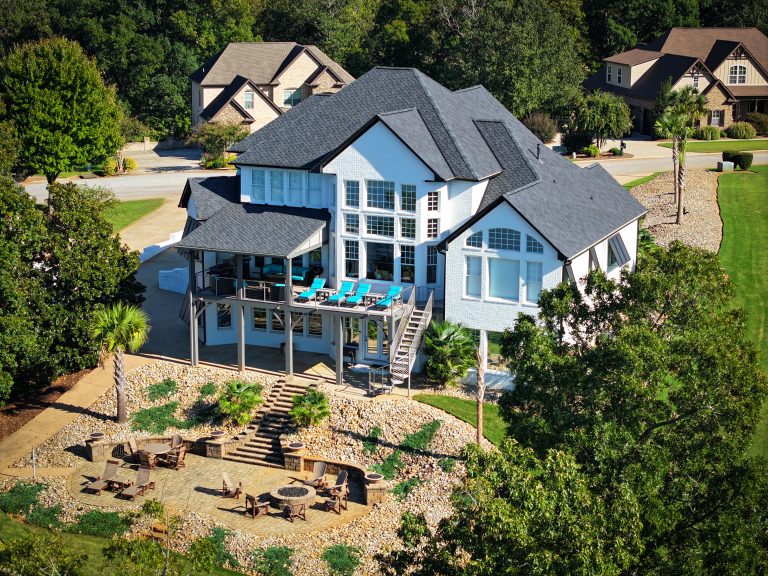 Modern residential home in Charlotte, NC, featuring a durable black shingle roof, spacious deck with lounge chairs, and landscaped yard with seating area, reflecting high-quality roofing services offered by Grier Roofing.