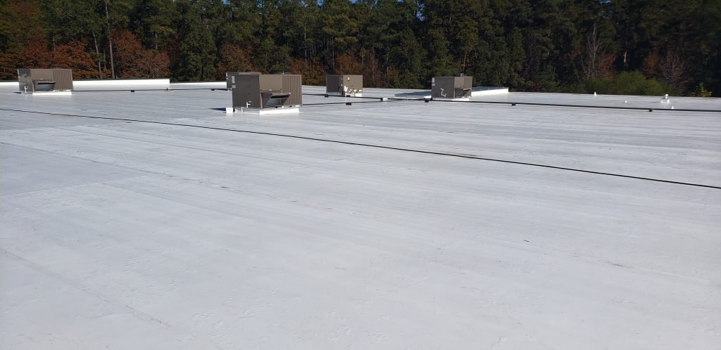 Commercial flat roofing system with HVAC units, showcasing a well-maintained surface in a wooded area, relevant to Grier Roofing's services in commercial roof installation and maintenance.