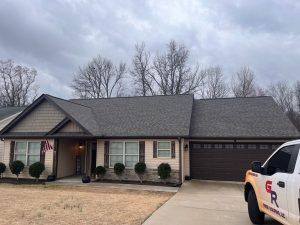Residential home featuring a newly installed asphalt shingle roof, showcasing Grier Roofing's quality craftsmanship, with a truck displaying the company logo parked in the driveway.