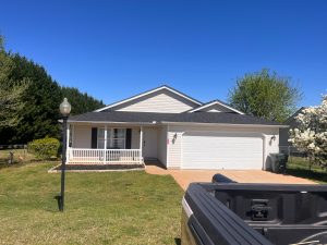 Residential home featuring a newly installed roof, showcasing modern design and curb appeal, surrounded by greenery and clear blue skies, emphasizing Grier Roofing's commitment to quality roofing solutions.