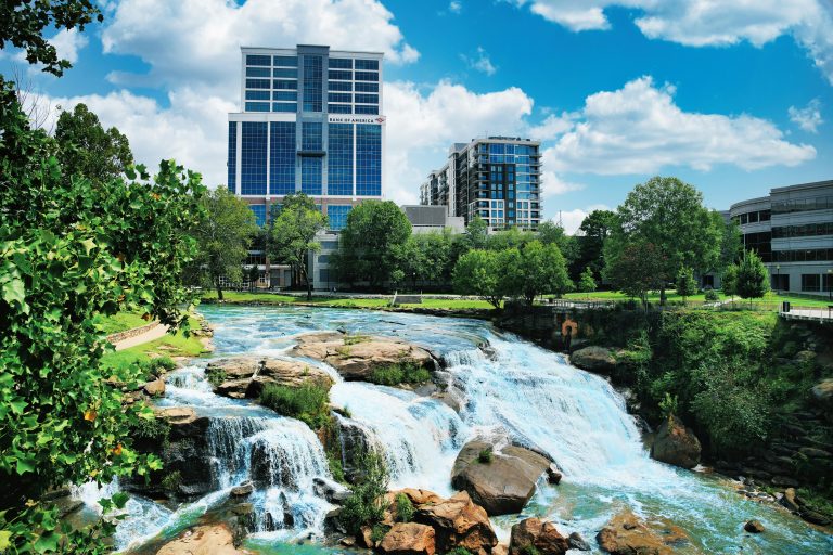 Greenville, SC downtown skyline featuring modern buildings and a scenic waterfall, highlighting the city's blend of natural beauty and urban sophistication.