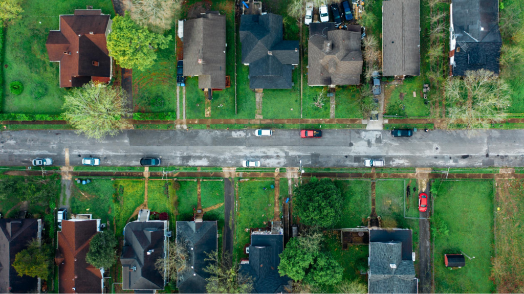 Aerial view of residential neighborhood showcasing houses with varying roof styles and conditions, emphasizing the importance of roof maintenance and replacement for property value and energy efficiency.