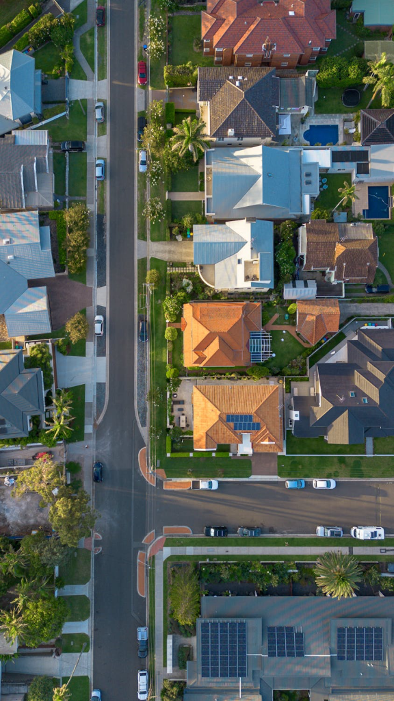 Aerial view of suburban neighborhood showcasing various houses with distinct roofing styles, including energy-efficient roofs, highlighting potential residential roof replacements and improvements related to tax benefits.