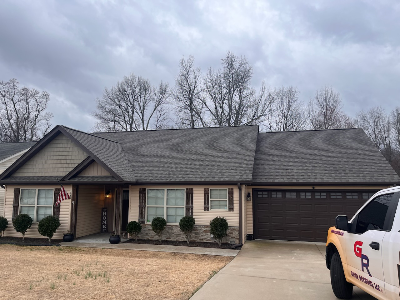 Residential home with a new roof, Grier Roofing truck parked in driveway, American flag displayed, showcasing quality roofing services in Spartanburg, Greenville, and surrounding areas.