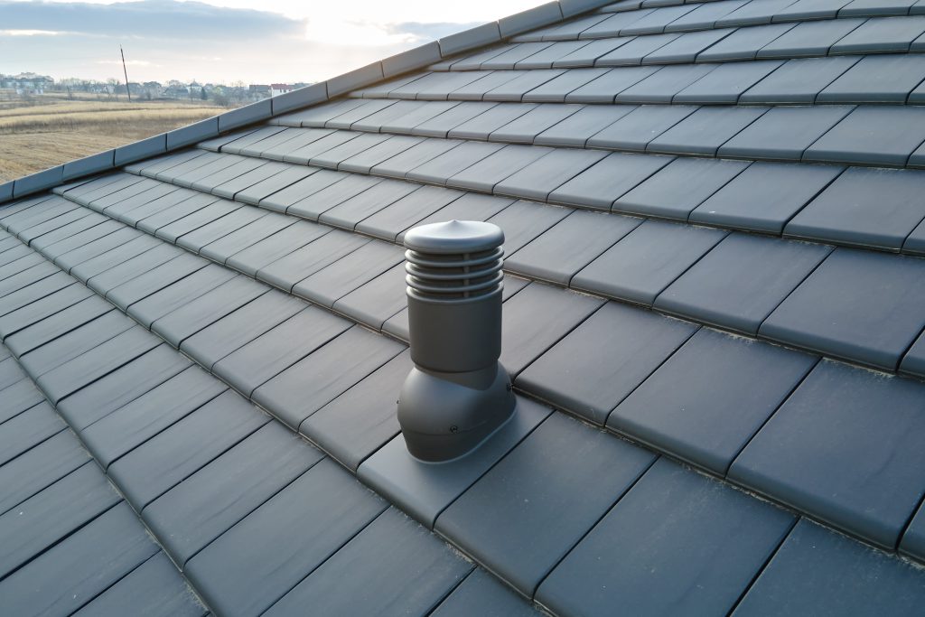 Close-up of a ventilation pipe on a flat roof, showcasing roofing material and design relevant to commercial properties.